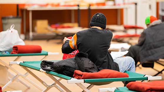 Photo of a guest seated on a cot at the Capuchin Community Services St. Ben's Winter Warming Center.